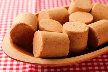 Fototapeta premium Pacoca, a traditional Brazilian sweet made of peanuts in cylindrical pieces, served in a wooden bowl on a checkered tablecloth
