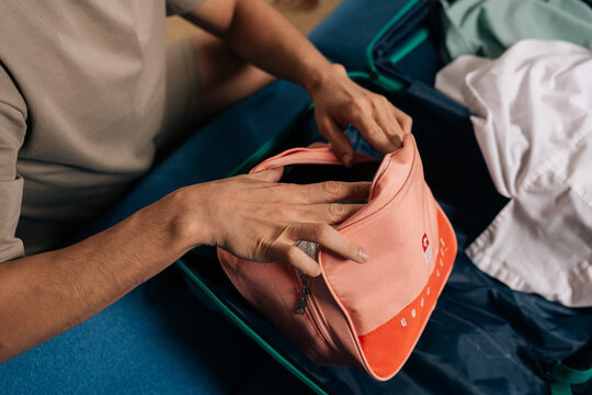 Person packing essential travel medicine bag into an open suitcase, preparing for a safe journey and prioritizing health during vacation and exploration, close-up, cropped shot
