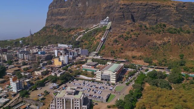 Tilt-up drone shot of Saptashrungi Devi Temple, one of the revered Sadetin Shakti Peethas in Maharashtra, revealing the hilltop shrine, scenic mountains and bright sky in Vani near Nashik