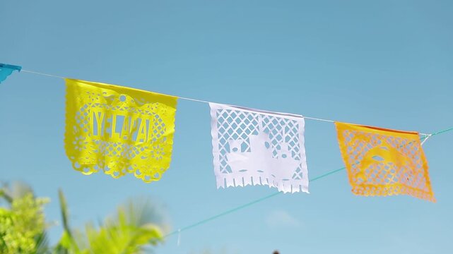Yelapa papel picado banners waving in the wind under a vibrant blue sky, Colorful papel picado banners with cut-outs hanging against a clear sky, celebrating local culture