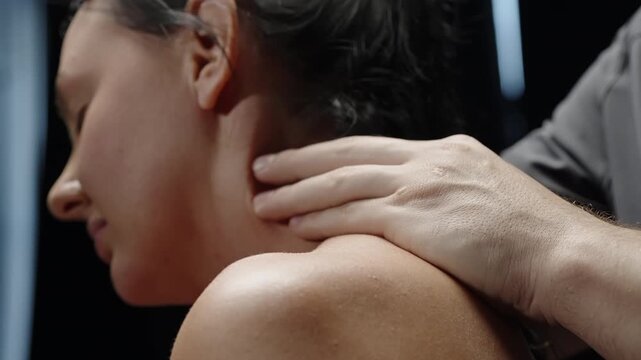 Close-up soothing shoulder and neck massage on a relaxed person, therapist s hand gently kneading trapezius muscles under soft lighting, conveying calm relief, wellness, and care.