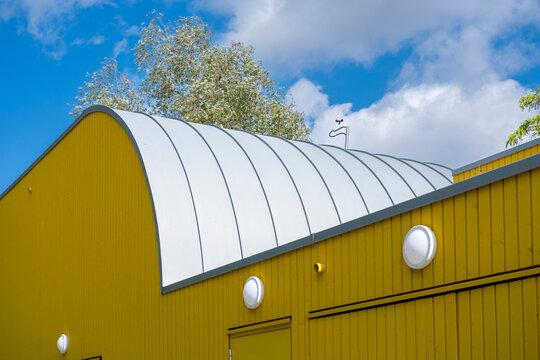 Yellow modern architecture exterior showing building facade and roof curve against open sky with minimal design for creative space