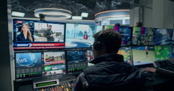 Backstage TV Station Production Control Room Directs a Live News Segment with Female Presenter as Technicians Switch Broadcast Sources, Monitor Graphics, Coordinate Studio Output. Zoom Out Shot
