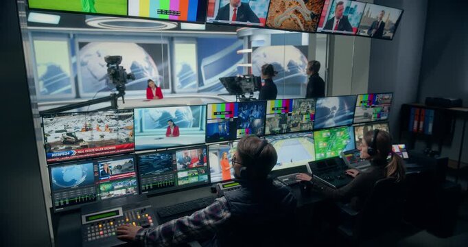 Backstage TV Station Production Control Room Manages a Live News Channel as Technicians Monitor Multiview Screens, Switch Broadcast Feeds, Coordinate Studio Cameras, and Cue the Anchor on Set.