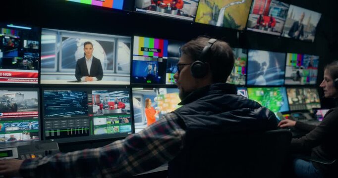 Backstage TV Station Production Control Room Captures Operators Coordinating Live News Broadcasting, Switching Anchor, Weather and Sport Channel Feeds While Monitoring Screens and Console Output.