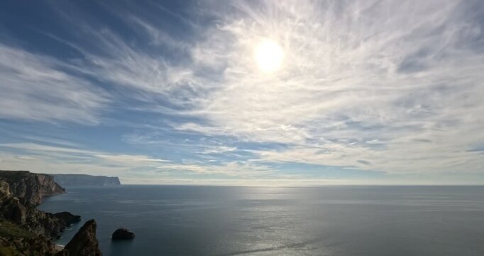 Clouds, ocean, timelapse of dramatic sky and cirrus clouds over majestic seaside cliffs and glittering deep water.