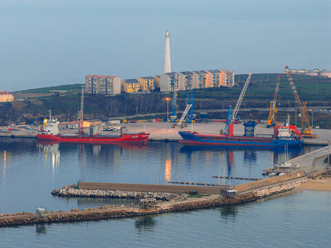 Aerial view of the harbor reflecting the twilight sky, with ships docked near the breakwater and the distant lighthouse standing tall, Vasto, Abruzzo, Italy.