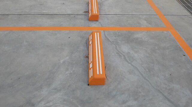 Empty parking space with orange lines on a concrete surface showing a clean layout and organized structure for vehicle positioning.
