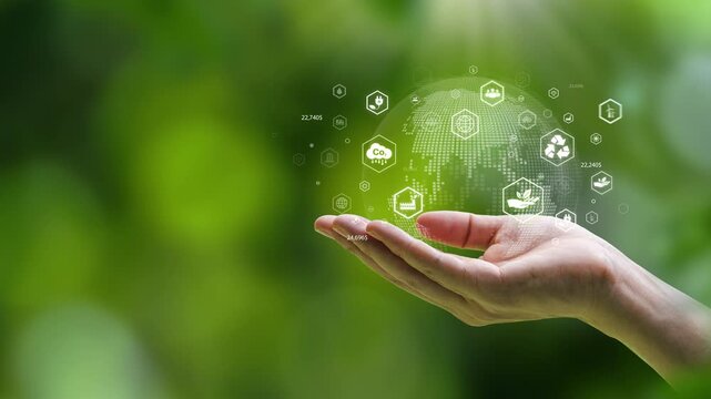 Close up of hand holding digital globe with ESG and green energy icons, representing sustainable business development and environmental conservation concept."