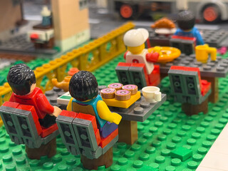 Obraz premium Lego minifigures at outdoor café tables with food and drinks