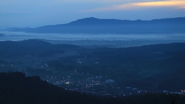 Natural video background of a high-angle atmosphere on a mountain that overlooks the surrounding scenery(mountains, trees,sea)from a scenic vantage point,with a wooden chair for sitting and resting