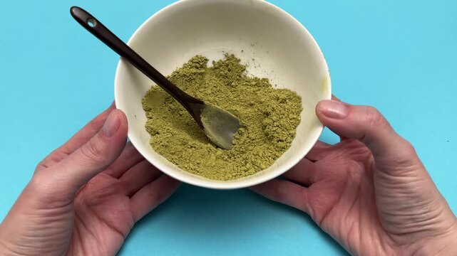 Woman holds white plate with henna and basma powder closeup