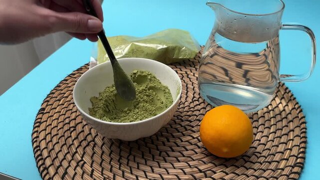 Woman stirs henna powder in plate preparing mixture for hair dyeing closeup