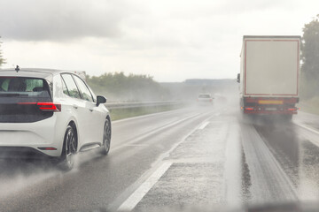 Naklejka premium Back tail view of many cars driving fast on wet highway road after rain in Europe. Automobile accident vehicle rush hour collapse. Transportation vacation seasonal stuck. Low visibility bad weather