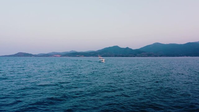 White Yacht Cruising on Blue Sea with Mountain Range at Dusk