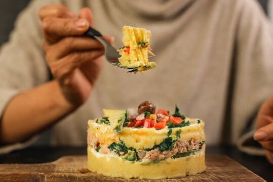 Unrecognizable person shows a piece of Causa rellena with a fork.
