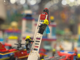 Fototapeta premium Toy firefighters climbing ladder in colorful rescue scene