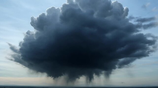 A large, dark cumulonimbus cloud with motion, indicating a stormy weather condition, against a blue