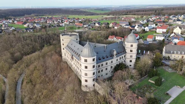 Drone performs a smooth small orbit from left to right around the complete historic castle structure.