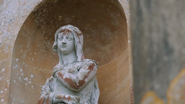 Artful statue of woman on side of historic building.