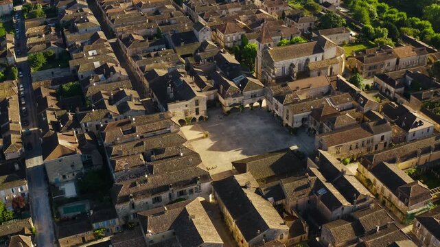 Central village square and organized street layout of the bastide town Monpazier in the heart of Dordogne. High altitude drone overview.
