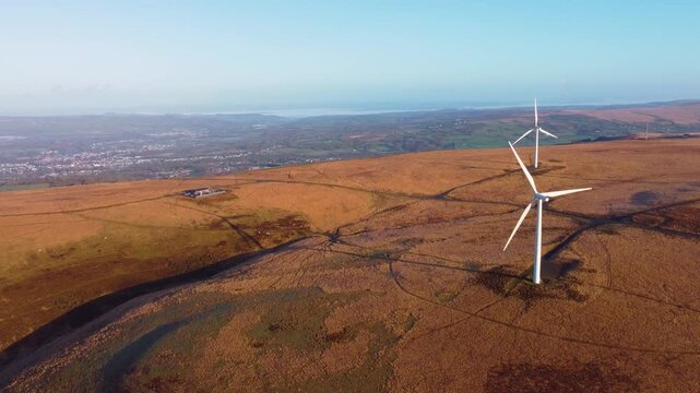 Sunrise Over Wind Farm with Turbines Suppling Electricity to Nearby Town with Substation acting as a bridge between high-voltage transmission lines and low-voltage distribution networks.