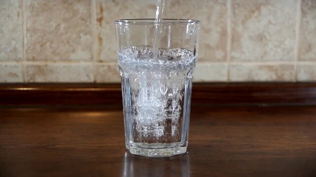 Clear water fills a glass and overflows, creating a soothing and refreshing visual moment.