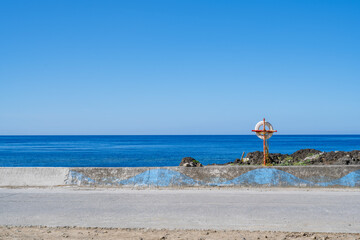 Fototapeta premium Lanyu, Taiwan: Minimalist coastal road landscape with lifebuoy and Pacific Ocean view.