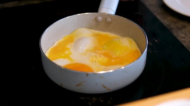  Process of breaking an egg on a frying pan for cooking sunny side up fried egg.