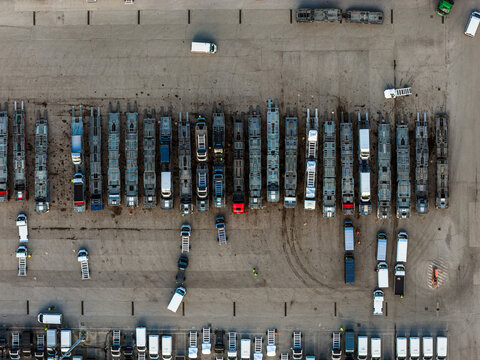Aerial view of a bustling parking lot filled with an array of vehicles, including trailers and cars, creating a geometric pattern from above, Atessa, Abruzzo, Italy.