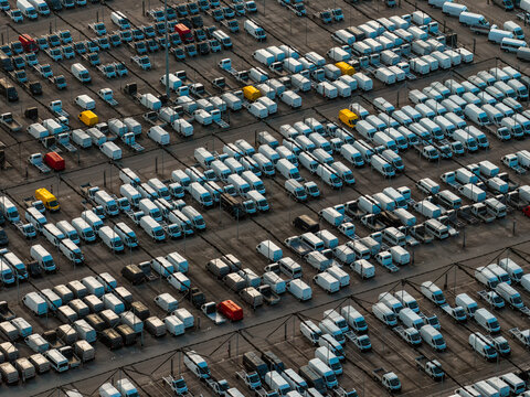 Aerial view of neat rows of parked vans, punctuated by splashes of red and yellow, create a mesmerizing geometric tapestry of commerce, Atessa, Abruzzo, Italy.