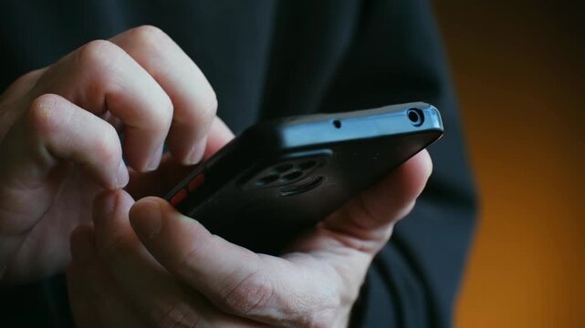 Close up male hands holding smartphone, with fingers tapping, scrolling on touchscreen for browsing, texting, using an application on social media. Hands using smartphone for scrolling and texting