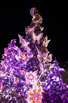 Purple Christmas tree decorated with butterflies at night during the Christmas season.