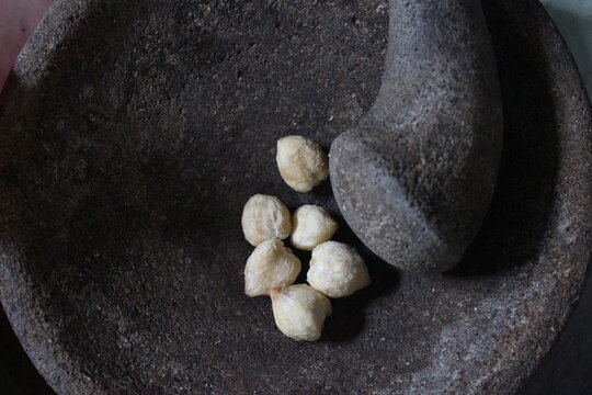 Candlenuts (Kemiri) in Traditional Stone Mortar with Pestle