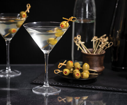 Dirty martini with olives on a pick on a dark background
