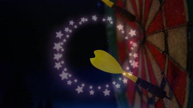 Animation of glowing star shaped fairy lights over close up of a yellow arrow on dart board