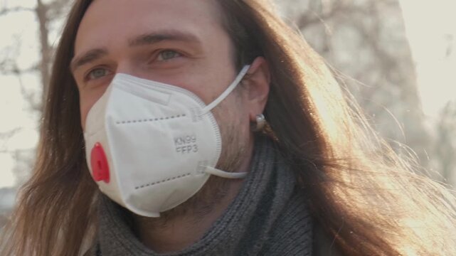 Bad Urban Ecology Air, Smog. Protection Mask for Health. Man Wearing Respirator Mask Outdoors, Long Hair And Gray Scarf, City Park, Calm Introspective Expression, CloseUp Cinematic Protective Mood