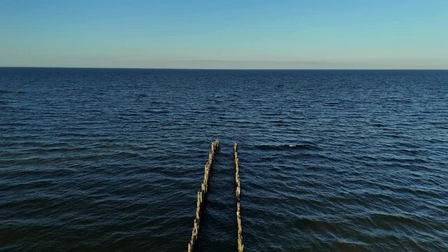Aerial Shot of Sea Waves Around Wooden Posts at Sunset Light