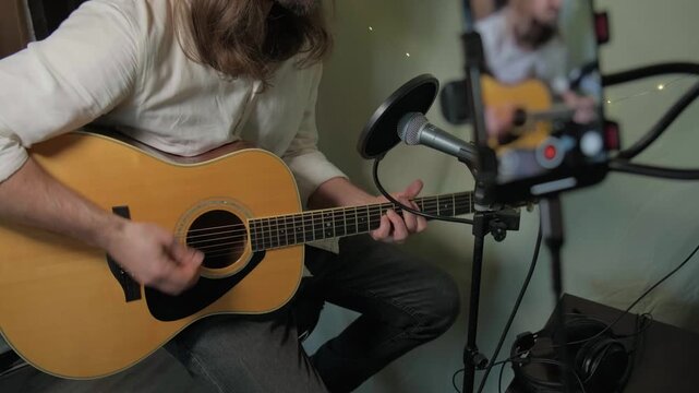 Acoustic guitar lesson streaming from home studio. Independent artist demonstrating chords and singing technique, sharing educational music content on social media platform