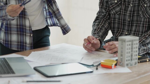 Engineers, architects, and technicians are analyzing structural design drafts in meetings with tabletop blueprints and discussing the project collaboratively in office meetings.