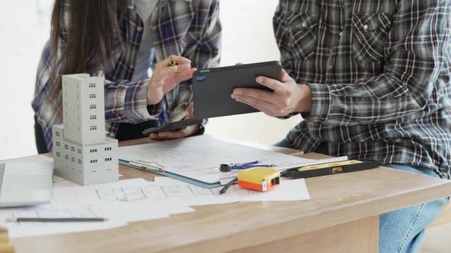 Engineers, architects, and technicians are analyzing structural design drafts in meetings with tabletop blueprints and discussing the project collaboratively in office meetings.
