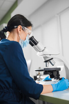 Expert In Viruses Examines Cultures Under Microscope While Following Strict Safety And Containment Procedures