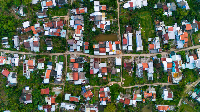 Aerial view of dwellings with red tiled roofs nestled amongst lush green vegetation create a vibrant patchwork, Hoi An, Quang Nam, Vietnam.