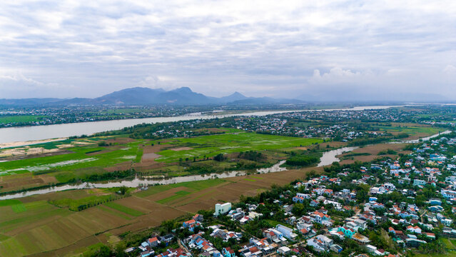Aerial view of the winding river snaking through the lush green landscape towards the distant mountains, Hoi An, Quang Nam, Vietnam.
