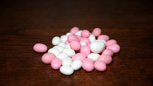 A handful of white and pink bean-shaped candies creates a soft, playful, and sweet visual scene.