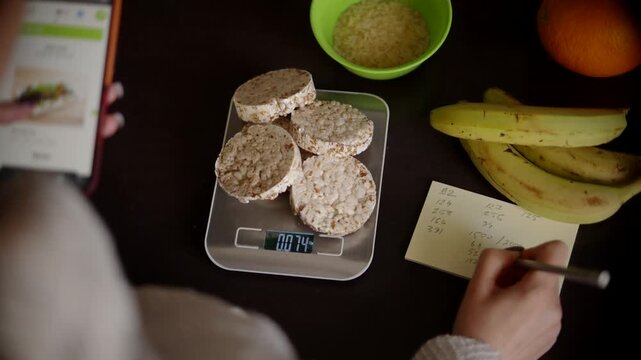 Weighing Rice Cakes On Electronic Kitchen Scales. Counting Calories And Writing Nutrition Data 