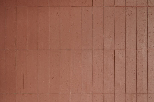 Vertical red terracotta tile wall texture. Modern architectural background with brick pattern and textured clay surface.