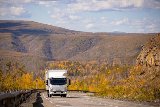 White japanese van moving by a mountain road
