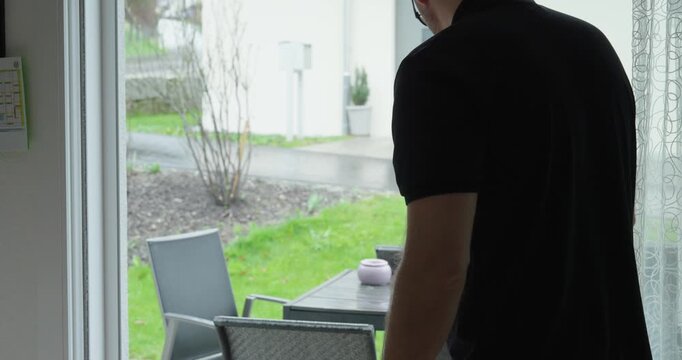 Man opening a terrace door with an insect screen to ventilate the room at home.