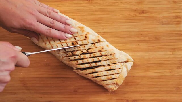 Chef hands cutting grilled shawarma wrap with a knife